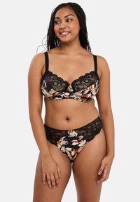 Reggiseno in pizzo floreale nero e mutandine coordinate con bordi scallop, un tessuto liscio con motivi di fiori arancioni e crema, e spalline regolabili.