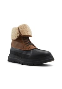 Botas de cuero marrón y goma negra con un cuello de felpa texturizada en tono beige. Cuentan con cierre de cordones y una suela robusta con dibujo para mayor tracción.