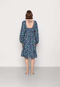 Vestido azul escuro com padrões florais, apresenta costas arredondadas, mangas bufantes e uma bainha em camadas com babados. Feito de tecido leve.