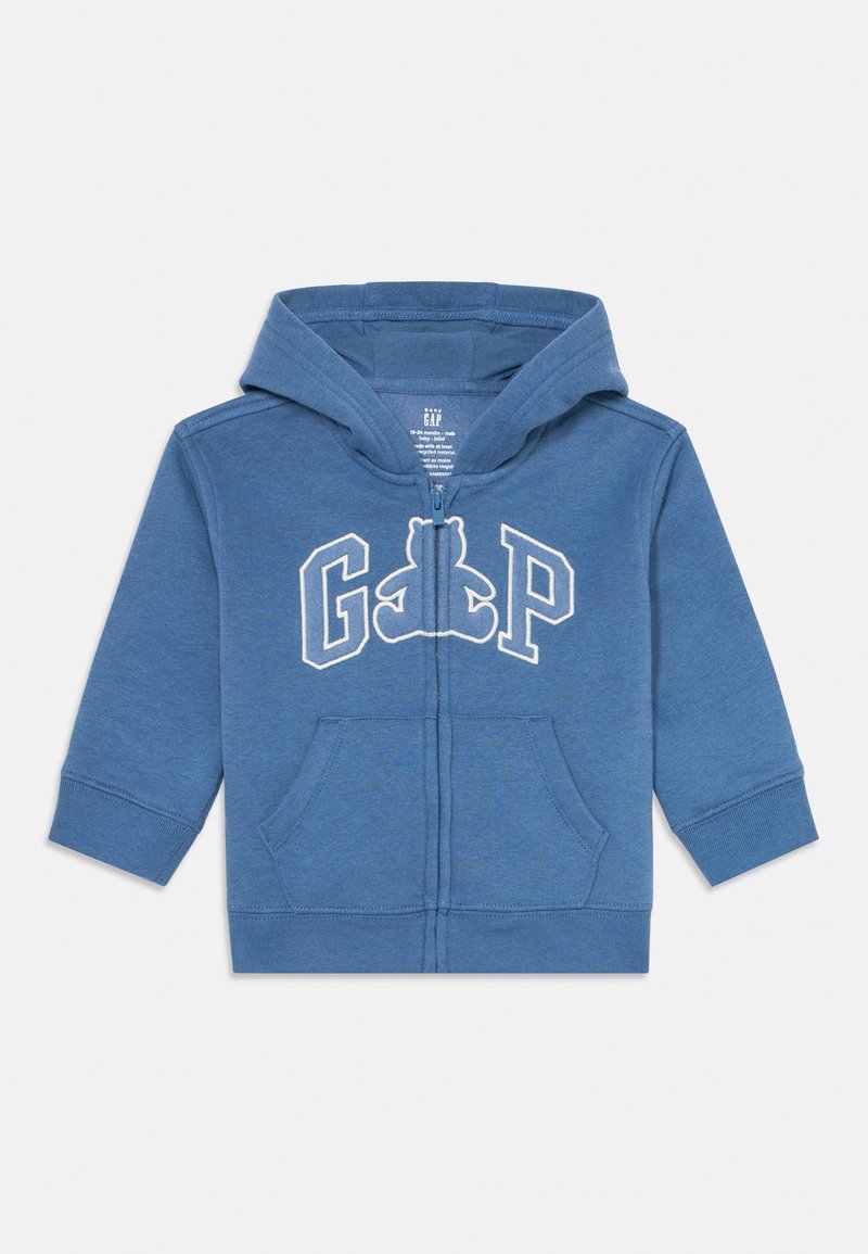 Modrá mikina s kapucňou pre batoľatá, so zipsom, prednými vreckami a bielym logom GAP s siluetou teddy medvedíka v strede.