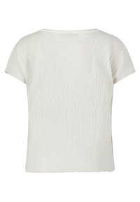 Haut blanc texturé à manches courtes avec une coupe ample. Le design présente un motif à côtes et un col légèrement arrondi. Détail en dentelle au niveau de l'ourlet.