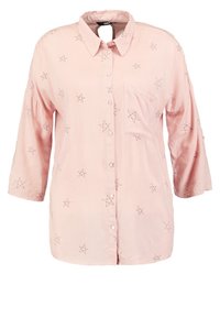 Blouse rose clair avec des motifs d'étoiles noires, fermeture à boutons sur le devant, col, et une poche poitrine unique, manches trois-quarts.
