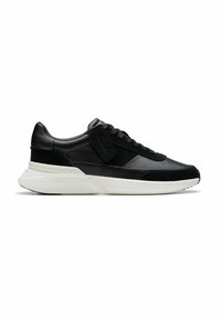 Schwarzer Low-Top-Sneaker mit Obermaterial aus Leder und Wildleder gemischt, dicker weißer Sohle und schwarzen Schnürsenkeln, seitlich auf weißem Hintergrund dargestellt.