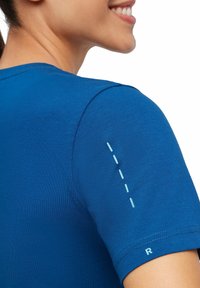 Maglietta azzurra a maniche corte realizzata in tessuto morbido, con un dettaglio decorativo di linea in azzurro chiaro sulla spalla e un piccolo accento "R" sulla manica.