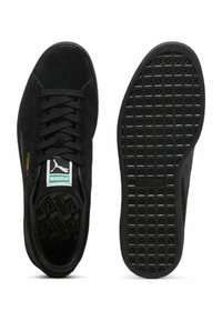 Sneaker in suede nero con suola in gomma piatta, punta rotonda, lacci sulla parte anteriore e etichetta verde del logo Puma sulla linguetta. Suola testurizzata con motivo a diamante.