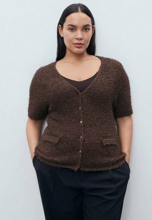 Cardigan marron texturé avec des manches courtes, un décolleté en V et des poches avant. Présente des boutons dorés et une coupe décontractée sur un pantalon sombre.