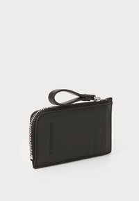 Portafoglio in pelle nera con chiusura a zip, dotato di un anello laterale, quattro slot per schede e branding impresso sul fronte. Texture liscia.