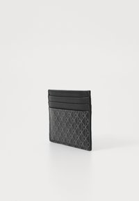 Porte-cartes en cuir noir avec un motif texturé et quatre fentes pour cartes sur le dessus. Design compact avec une finition épurée et une texture mate.