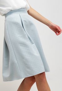 Gonna a-line azzurro chiaro con motivo testurizzato, pieghe in vita e finitura liscia. Progettata per una silhouette valorizzante.