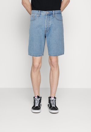 Shorts en denim bleu clair à coupe droite, ourlet cousu et poches avant, associés à des baskets montantes noires.