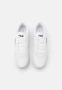 Hvite sneakers med glatt skinnmateriale, avrundet tå, snøring, Fila-logo i blått og rødt. Har perforerte detaljer på tåboksen.