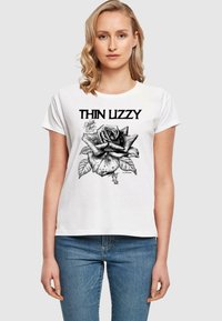 Hvid bomulds t-shirt med et sort grafisk design af en rose og teksten "THIN LIZZY" ovenfor, med korte ærmer og en afslappet pasform.