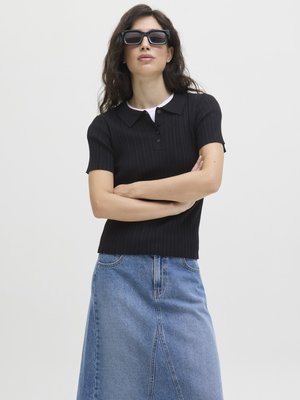 Polo shirt manica corta a righe nere con dettaglio dei bottoni, abbinato a una gonna A-line in denim azzurro chiaro. Modella con occhiali da sole scuri a forma quadrata.