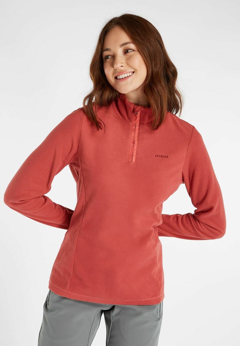 Rød fleecepullover med halvlukning, højt krave og logo detalje på brystet. Lange ærmer med en glat tekstur og afslappet pasform.