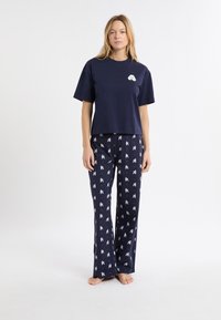 Granatowy bawełniany komplet piżamowy z krótki rękawem z logo oraz spodniami w deseń z nadrukiem małych białych postaci.