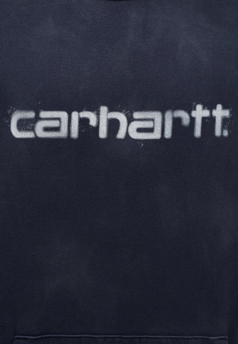 Dunkelblaues Sweatshirt mit einem großen, weißen "carhartt."-Logo auf der Vorderseite. Der Stoff hat ein strukturiertes, weiches Erscheinungsbild.