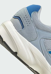 Gray athletic shoe with mesh and suede materials, blue accents, textured surface, featuring a thick white sole and CLOUDFOAM branding.