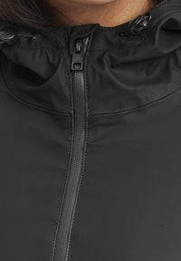 Czarna kurtka z kapturem, zapinana na pełny zamek, z gładką fakturą i regulacją przy kołnierzu za pomocą sznurka. Minimalistyczny design, bez wzorów.