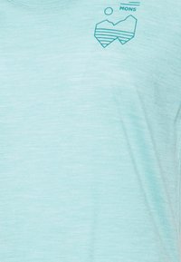 Ljusblå t-shirt med kort ärm i mjukt material har en berggrafik och soltryck i teal på vänstra bröstet.