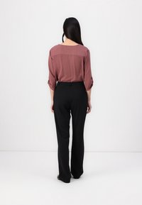 Bordeaux lange mouwtop met een ronde hals en opgerolde mouwen, gecombineerd met zwarte wijde broek. Glad materiaal, casual pasvorm.