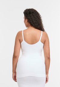 Body bianco senza cuciture con spalline regolabili, una vestibilità modellante e una texture morbida e elastica. Progettato per il comfort e per essere indossato a strati.