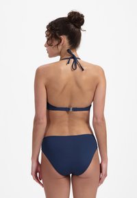 Marineblauwe bikini-set met een haltertop met striksluiting en sluiting, gecombineerd met onderstukken met gemiddelde bedekking, vervaardigd uit gladde stof.