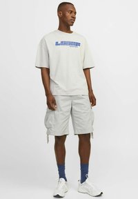 Lysegrå oversized t-shirt med blå "LOOOSR JACK & JONES" print, parret med matchende cargo shorts og hvide sneakers med blå accenter.