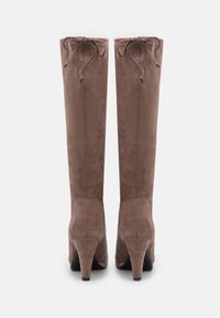 Bottes hauteur genou en daim marron avec un bout pointu et un talon effilé. Des lacets sont présents en haut pour un ajustement réglable.