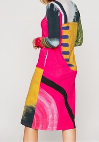 Vestido de manga larga colorido con patrones abstractos en rosa, amarillo, verde y negro, con una textura suave y una silueta ajustada.