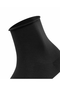Calcetín negro ajustado fabricado con una tela suave y elástica, con un puño ancho. La textura es lisa y uniforme, sin patrones ni acentos visibles.