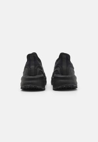 Baskets de sport noires avec une surface texturée, une semelle rembourrée et un design épuré avec un talon arrondi et une languette de talon renforcée.
