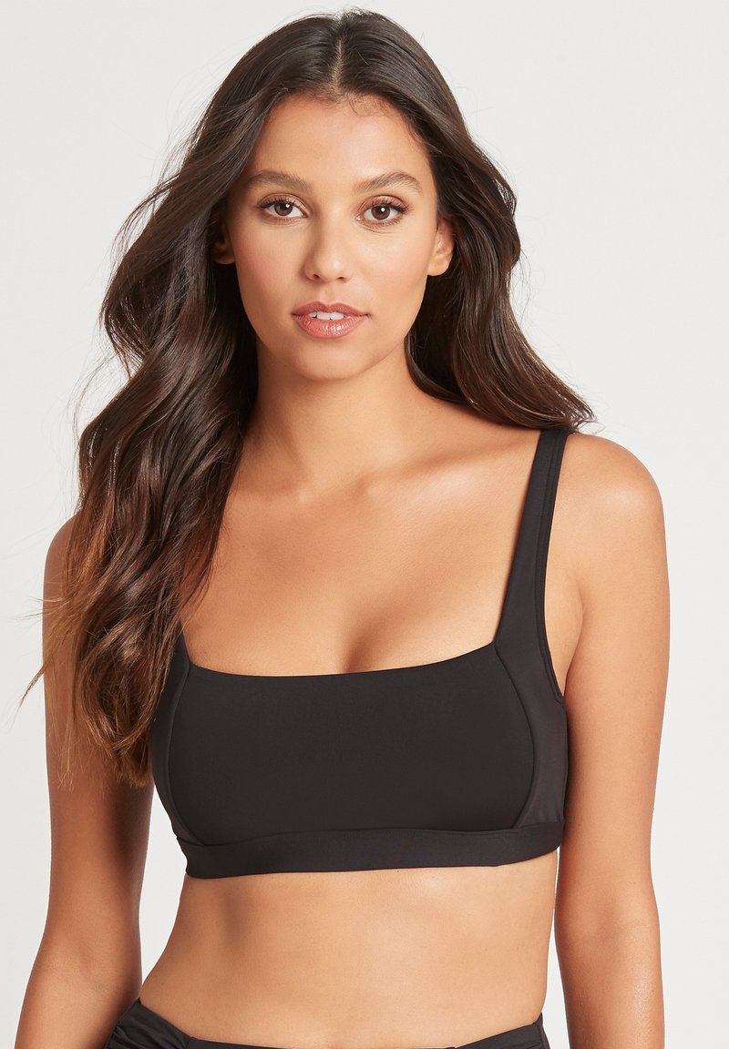Zwarte bralette met brede bandjes, vierkante halslijn en een zachte textuur. Eenvoudig ontwerp dat geschikt is voor lagen of casual draag.