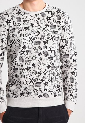 Grauer Pullover mit schwarzem Grafikdruck, der verschiedene Symbole wie Totenköpfe, Sterne und Friedenszeichen enthält. Gerippte Bündchen und Taillenbund.