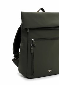 Sac à dos vert avec un design enroulable, fabriqué en matériau lisse et résistant à l'eau. Comprend une poche zippée à l'avant et des bretelles réglables.