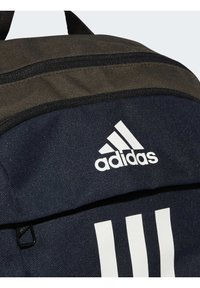Zaino blu navy realizzato in un tessuto testurizzato, con un pannello superiore grigio scuro, logo Adidas bianco e tre strisce bianche sul davanti.