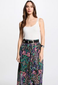 White tank top with lace straps paired with a multi-colored, floral and animal print long skirt, belted with a black belt and silver hardware.