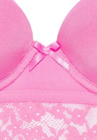 Sostén acolchado rosa con tela suave en los copas y un patrón de encaje floral en la banda, acentuado con un pequeño lazo de satén en el centro.