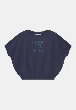 Tmavě modré oversized tričko vyrobené z měkkého materiálu. Má kulatý výstřih, krátké rukávy a logo "TOMMY HILFIGER" v kontrastní modré barvě.