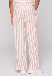Weite Hosen aus leichtem Stoff mit vertikalen rosa und blauen Streifen. Sie haben eine hohe Taille und ein dezentes Logo auf der Rückseite.