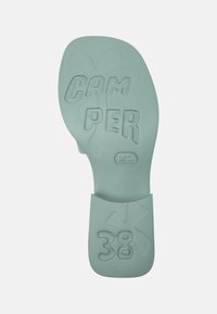 Light green rubber shoe sole with embossed text "CAMPER" and size "38," featuring a floral design and smooth texture.