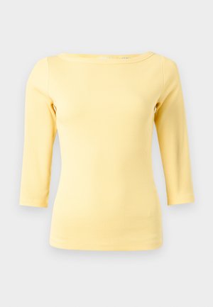 Haut à manches longues jaune à côtes, avec un grand col et une silhouette ajustée. Texture lisse sans accents ni motifs visibles.