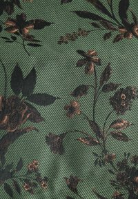 Zöld textil, fekete és barna virágmintával, amelynek felülete texturált és bordázott, fokozva ezzel a mélységet és a vizuális érdekességet.