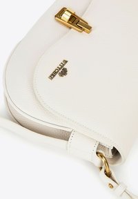 Bolso cruzado de piel blanca con herrajes dorados, superficie texturizada, cierre de presión y logotipo de la marca. Cuenta con una correa larga y ajustable.
