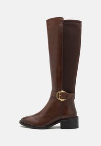 Knee-high brązowe skórzane i materiałowe botki z akcentem złotego zapięcia, zaokrąglonym czubkiem i gruba czarną obcasem. Gładka faktura z detalami w formie szwów.