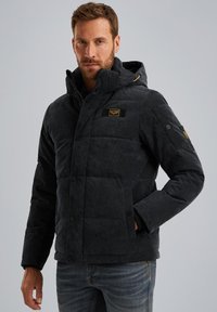 Veste matelassée à capuche de couleur gris foncé, avec des boutons-pression et un patch logo sur la poitrine. Dotée d'un tissu texturé et de poches latérales.
