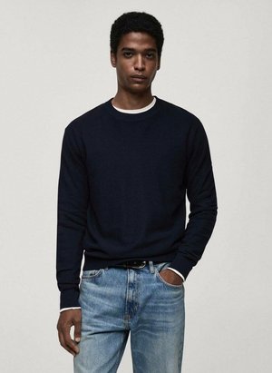 Felpa a maglia blu navy con collo rotondo, polsini e orlo a coste. Indossata con jeans blu chiaro, con una cintura nera e una maglietta bianca sotto.