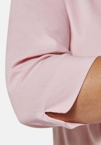 Rosa Baumwollhemdärmel mit gerolltem Umschlag und geschlitztem Öffnungsdesign. Weiche Textur mit sauberen Nähdetails.