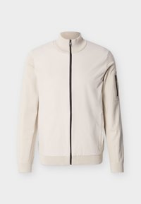 Μπεζ μπουφάν με ολόκληρο φερμουάρ, με ριμπ γιακά, μανσέτες, τελείωμα και τσέπη με φερμουάρ στο αριστερό πάνω μανίκι.