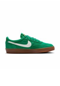 Zöld velúr sportcipő fehér Nike pipa logóval, lapos fűzőkkel, párnázott nyelvvel és barna gumitalppal. Minimális dizájn, alacsony fazon.