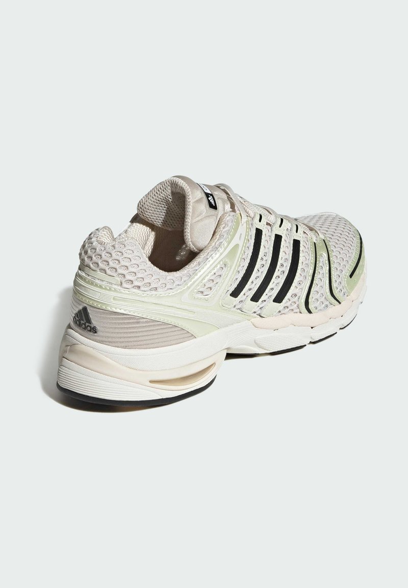 Sport Schuhe mit einem Obermaterial aus hellem Beige-Mesh, schwarzen Streifen, grünen Akzenten und einer strukturierten Ferse. Gepolsterte Sohle mit tapered Design.